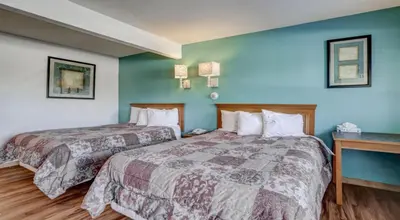 two beds in a hotel room with blue walls at Americas Best Value Inn Greeley in Evans