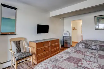 a bedroom with a bed and a dresser and a tv at Americas Best Value Inn Greeley in Evans