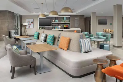 a living room with a couch and tables and chairs at Home2 Suites By Hilton Longmont in Longmont