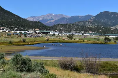 a lake with a town and mountains in the background at Estes Lake Lodge in Estes Park