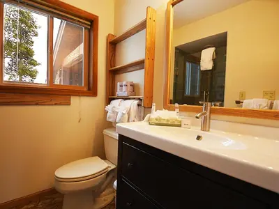 a bathroom with a toilet and a sink and a mirror at 61 Jabberwocky Home by Stay Winter Park in Fraser