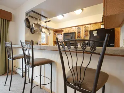 a kitchen with a bar with chairs and a counter at 61 Jabberwocky Home by Stay Winter Park in Fraser
