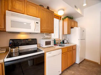a kitchen with white appliances and wooden cabinets at Winterstar Building G #3 by Stay Winter Park in Fraser
