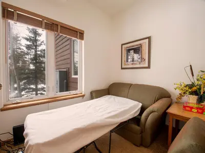 a bed in a room with a chair and a window at Winterstar Building G #3 by Stay Winter Park in Fraser