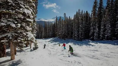 a group of people skiing down a snow covered slope at Winterstar Building G #3 by Stay Winter Park in Fraser