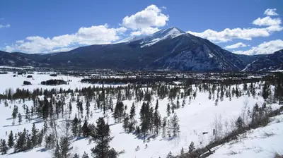 a snow covered mountain with a town and trees at Heart of Frisco Condo in Frisco