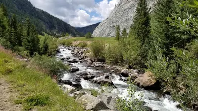a river in the mountains with rocks and trees at Heart of Frisco Condo in Frisco