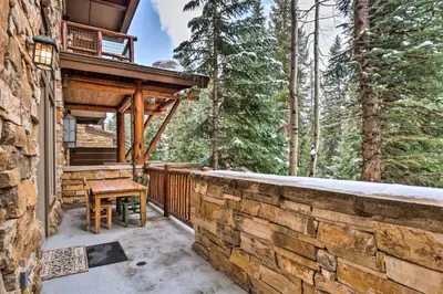 a patio with a wooden table on a stone wall at The Timbers Ski-In, Ski-Out 1 Bedroom Plus Murphy in Keystone