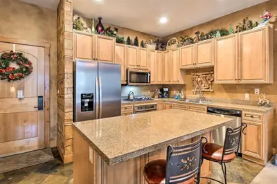 a kitchen with wooden cabinets and a stainless steel refrigerator at The Timbers Ski-In, Ski-Out 1 Bedroom Plus Murphy in Keystone
