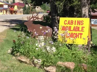 a yellow sign with a deer statue next to a street at Columbine Cabins in Grand Lake