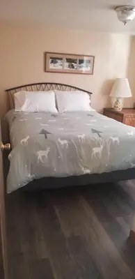 a bed with a white comforter with horses on it at Columbine Cabins in Grand Lake