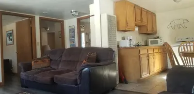 a living room with a couch and a kitchen at Columbine Cabins in Grand Lake