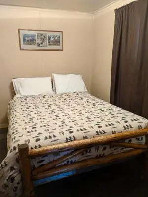 a bedroom with a bed with a comforter on it at Columbine Cabins in Grand Lake