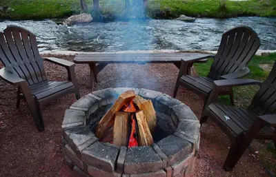 a fire pit with two chairs and a table at Murphy's River Lodge in Estes Park