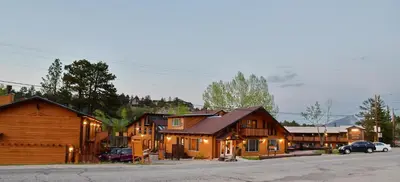a group of wooden buildings with cars parked in front at Murphy's River Lodge in Estes Park