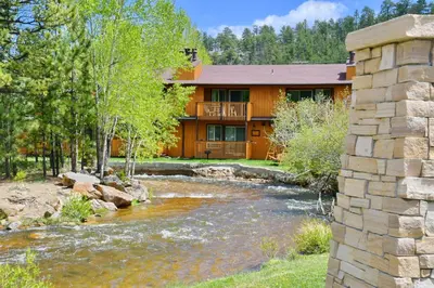 a house with a river in front of it at Murphy's River Lodge in Estes Park