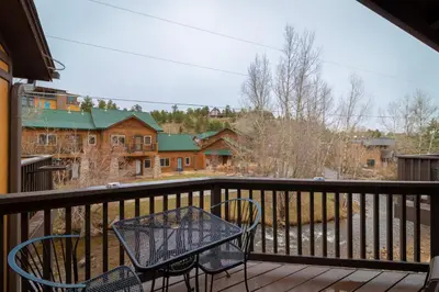 a table and chairs on a balcony with a view at Murphy's River Lodge in Estes Park
