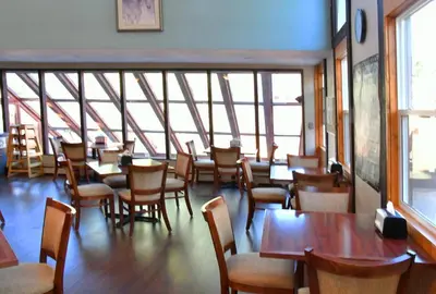 a dining room with tables and chairs and windows at Murphy's River Lodge in Estes Park