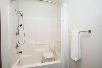 a bathroom with a shower and a bath tub with a chair at Super 8 by Wyndham Kremmling in Kremmling
