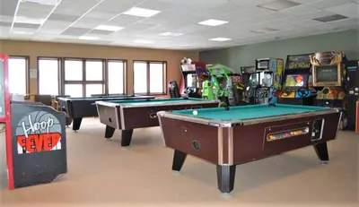 a room with three pool tables and arcade machines at The Inn at Silvercreek in Granby