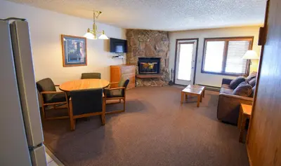 a living room with a table and a fireplace at The Inn at Silvercreek in Granby