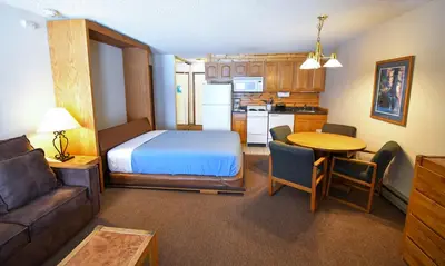 a room with a bed and a kitchen with a table at The Inn at Silvercreek in Granby