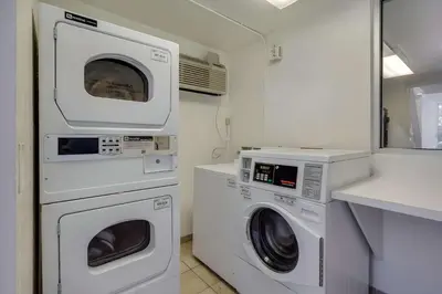 a laundry room with two washing machines and a sink at Park Inn by Radisson, Lakewood in Lakewood