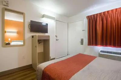 a bedroom with a bed and a mirror and a red curtain at Park Inn by Radisson, Lakewood in Lakewood