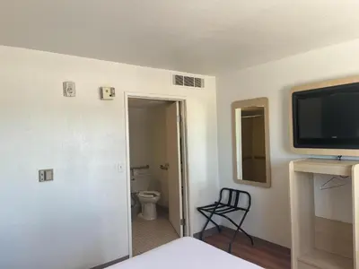 a room with a bathroom with a toilet and a television at Motel 6 Fort Collins, CO in Fort Collins