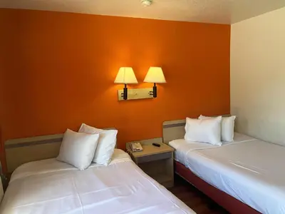 two beds in a room with an orange wall at Motel 6 Fort Collins, CO in Fort Collins
