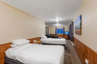 a hotel room with three beds and a desk at Discovery Lodge in Estes Park