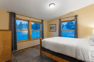 a bedroom with a bed and two windows at Discovery Lodge in Estes Park