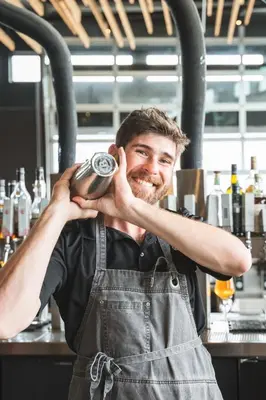 a man wearing an apron holding a camera in a kitchen at The Source Hotel in Denver