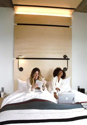 two women sitting on a bed with their laptops at The Source Hotel in Denver
