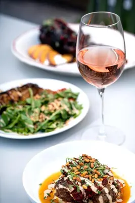 a table with plates of food and a glass of wine at The Source Hotel in Denver