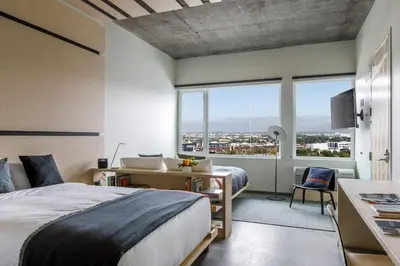 a bedroom with a bed and a desk and a large window at The Source Hotel in Denver