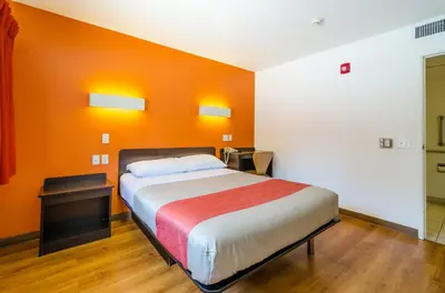 a bedroom with a bed with an orange wall at Motel 6 Thornton in Thornton