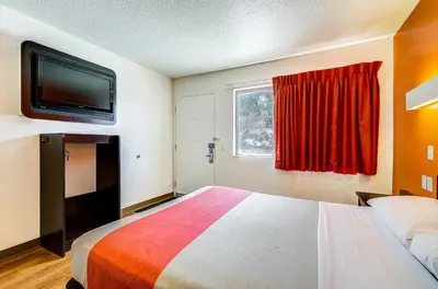 a hotel room with a bed and a flat screen tv at Motel 6 Thornton in Thornton