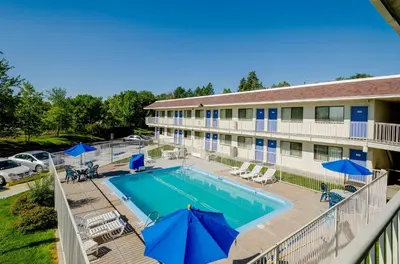 an overhead view of a pool at a hotel with blue umbrellas at Motel 6 Thornton in Thornton