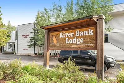a sign for a river bank lodge in a parking lot at 2914 River Bank Lodge - Keystone in Keystone