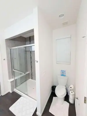 a white bathroom with a shower and a toilet at Den Haven Entire Home Near DIA With Three Bedrooms And Private En Suite Baths in Denver