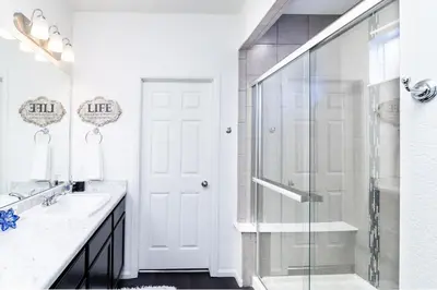 a white bathroom with a shower and a glass door at Den Haven Entire Home Near DIA With Three Bedrooms And Private En Suite Baths in Denver