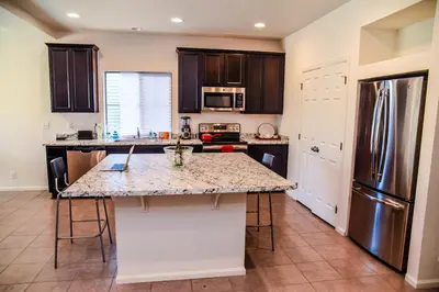 a kitchen with a granite counter top and a refrigerator at Den Haven Entire Home Near DIA With Three Bedrooms And Private En Suite Baths in Denver