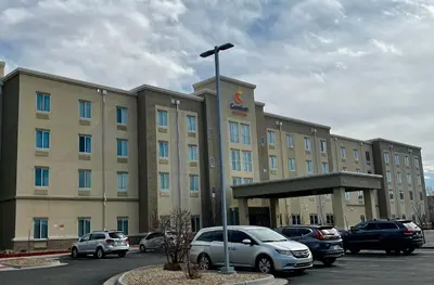 a large building with cars parked in a parking lot at Comfort Suites Denver International Airport in Denver