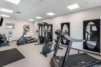 a gym with several tread machines and mirrors at MainStay Suites Denver International Airport in Denver