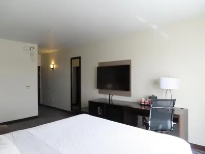 a bedroom with a bed and a desk with a television at Sleep Inn & Suites Denver International Airport in Denver