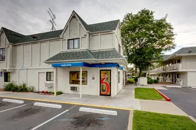 a white building with a red door on a street at Motel 6-Wheat Ridge, CO - West - Denver North in Wheat Ridge