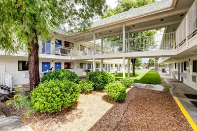 an exterior view of a building with trees and bushes at Motel 6-Wheat Ridge, CO - West - Denver North in Wheat Ridge