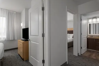 a hotel room with a bed and a tv and a door at TownPlaces Suite Denver Airport at Gateway Park in Denver