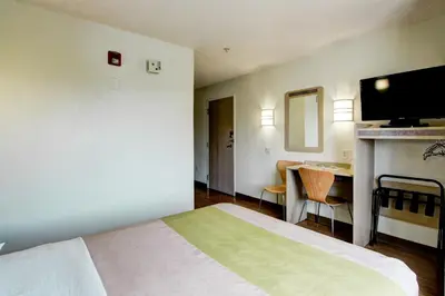 a hotel room with a bed and a table and a television at Super 8 by Wyndham Aurora East in Aurora